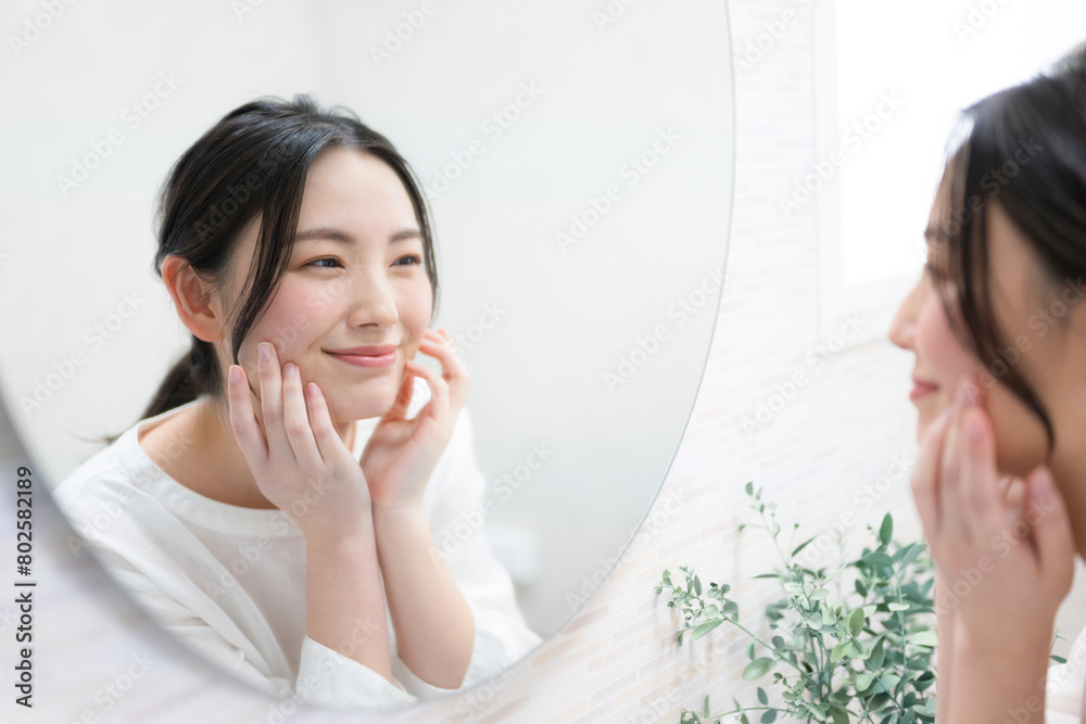 鏡を見ながら肌の質感を気にする女性 スキンケアや美容のイメージ 鏡を見ながら肌の質感を気にする女性 スキンケアや美容のイメージ