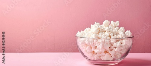 Fresh cottage cheese placed in a transparent bowl on a pink surface  with empty space - representing the idea of wholesome nutrition  dietary habits  and food choices.