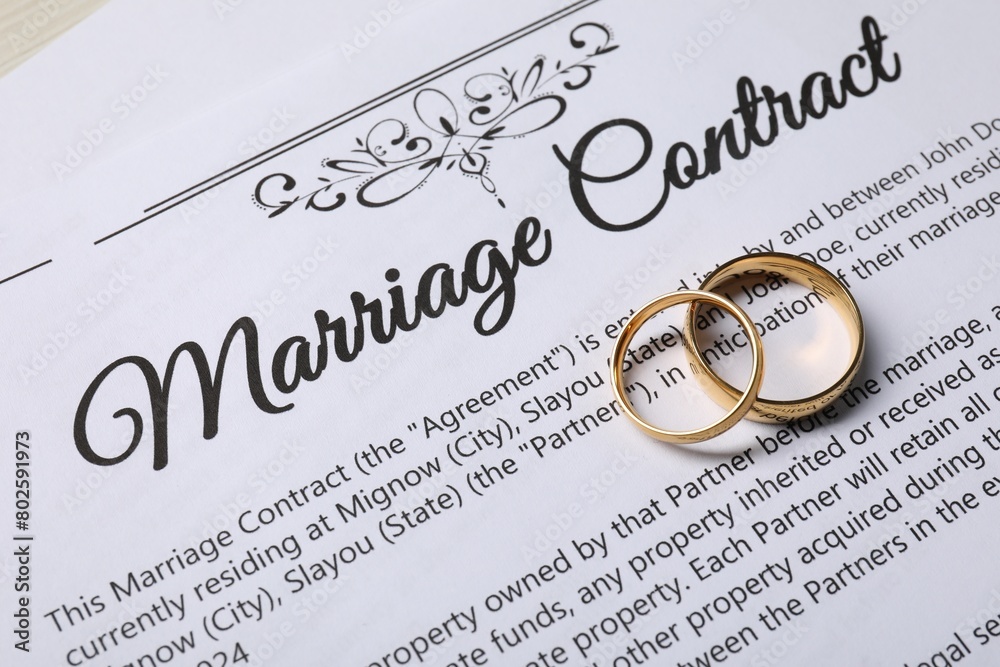 Marriage contract and gold rings on table, above view Marriage contract and gold rings on table, above view