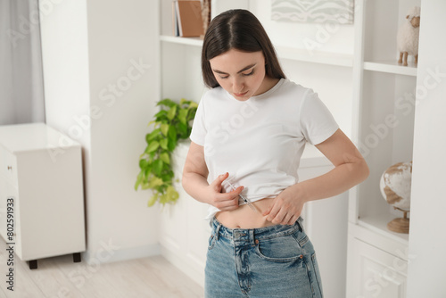 Diabetes. Woman making insulin injection into her belly at home