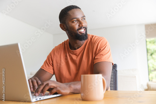 At home, African American male homeowner using laptop, looking away photo