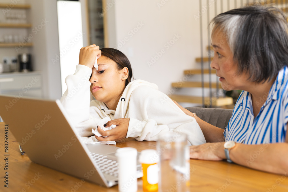 Asian grandmother, consoling biracial teen granddaughter on video call at home Asian grandmother, consoling biracial teen granddaughter on video call at home