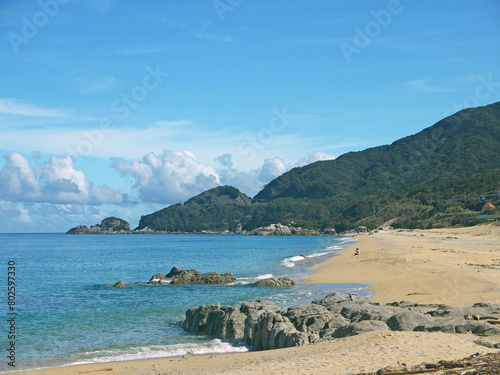 Yakushima coast panorama on sunny day, Inakahama sandy beach turquoise sea water, blue sky, distant Kuchierabujima isalnd