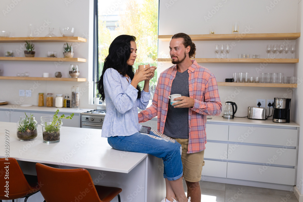 Diverse couple enjoying coffee in modern kitchen at home