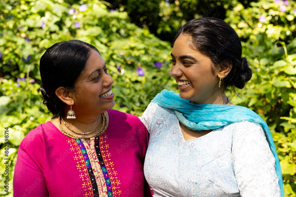 Indian mother and teenage daughter smiling at each other outdoors Indian mother and teenage daughter smiling at each other outdoors