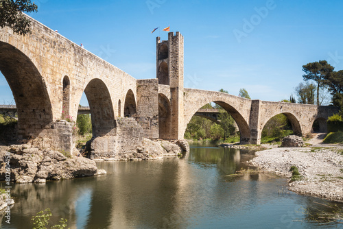 A bridge spans a river with a view of a castle in the background