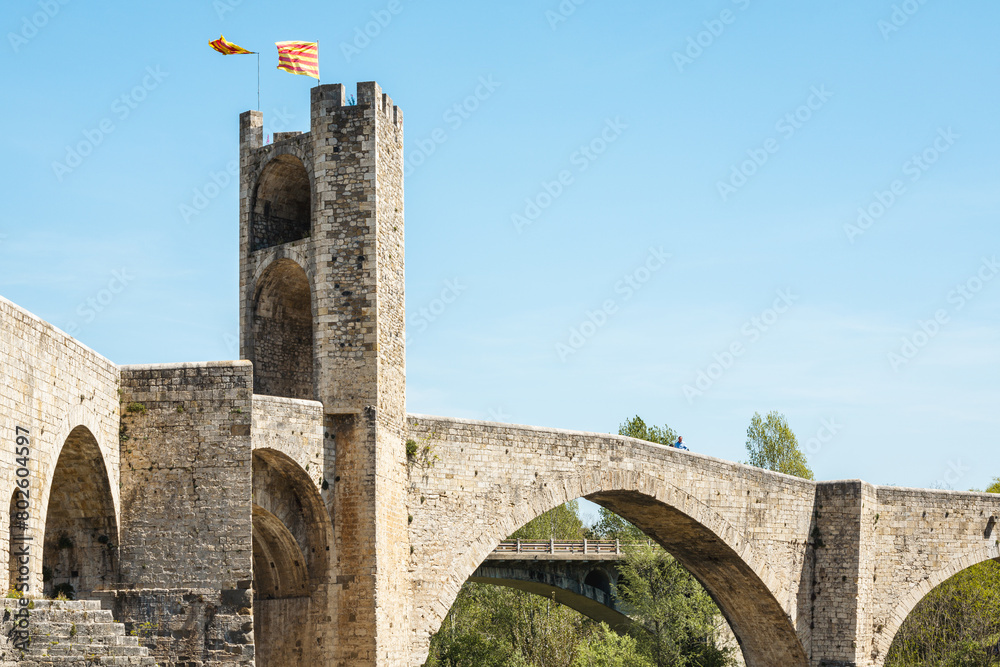 A bridge with a tower in the background and a flag on top of the tower