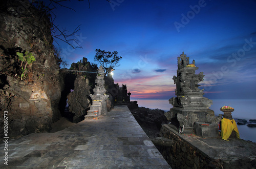 view of the temple with a dark blue and red twilight sky and next to it is the ocean at Batubolong Lombok Temple photo