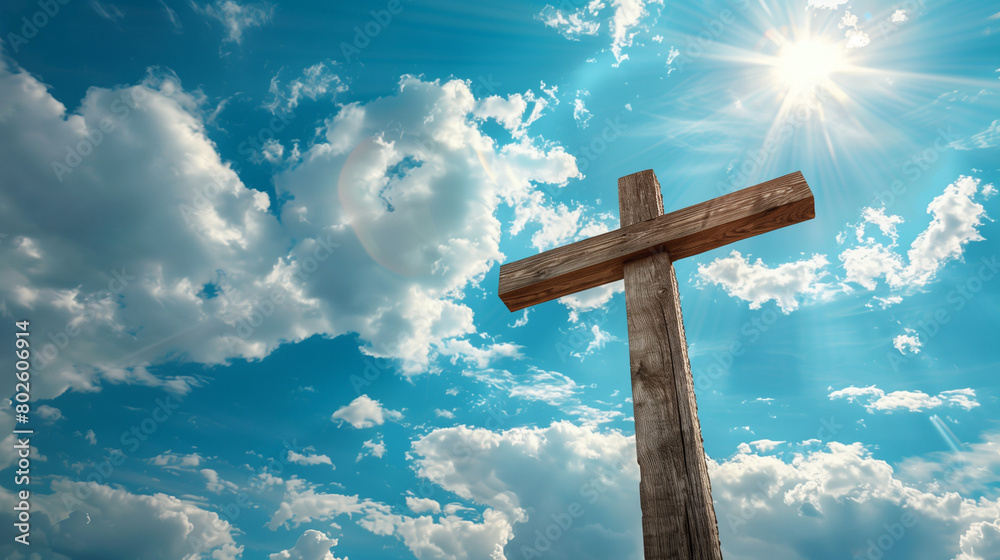 Wooden cross on a blue sky with clouds and sun rays in the background