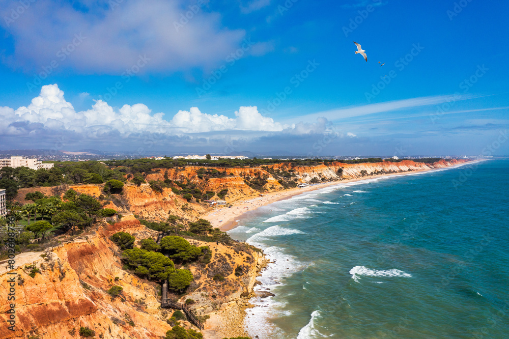 Fototapeta premium Aerial seascape and coastline cliffs of Praia do Barranco das Belharucas beach, in Algarve region in South Portugal. Praia do Barranco das Belharucas beach, Albufeira, Algarve, Portugal.