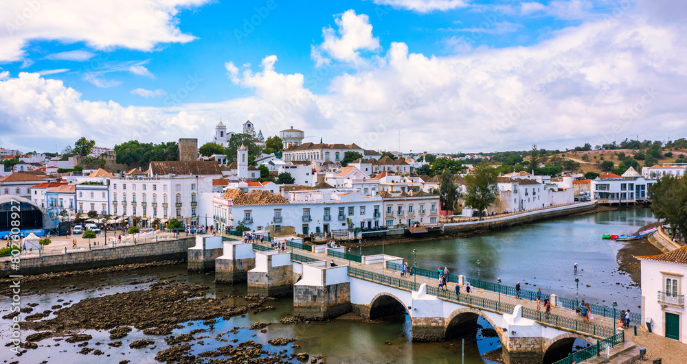 Obraz premium View on historic town of Tavira with Roman bridge over River Gilao, Algarve, Portugal. Cityscape of the Tavira old town with Clock tower, St Marys church, Algarve region, Portugal.