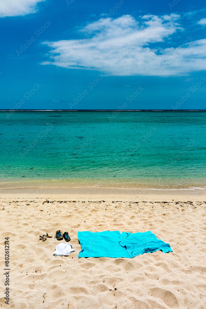Flip flops and blue beach towel on sand close to the sea Flip flops and blue beach towel on sand close to the sea