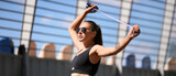 Sporty young woman in sunglasses with skipping rope outdoors