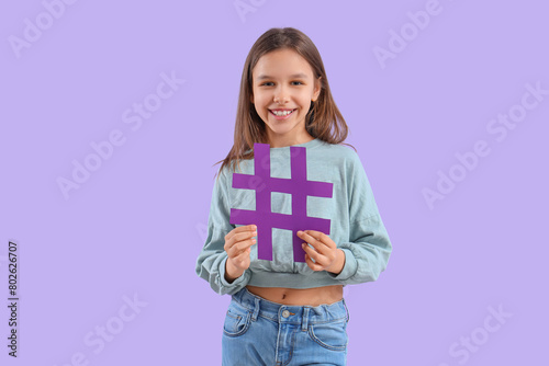 Cute teenage girl with hashtag on lilac background