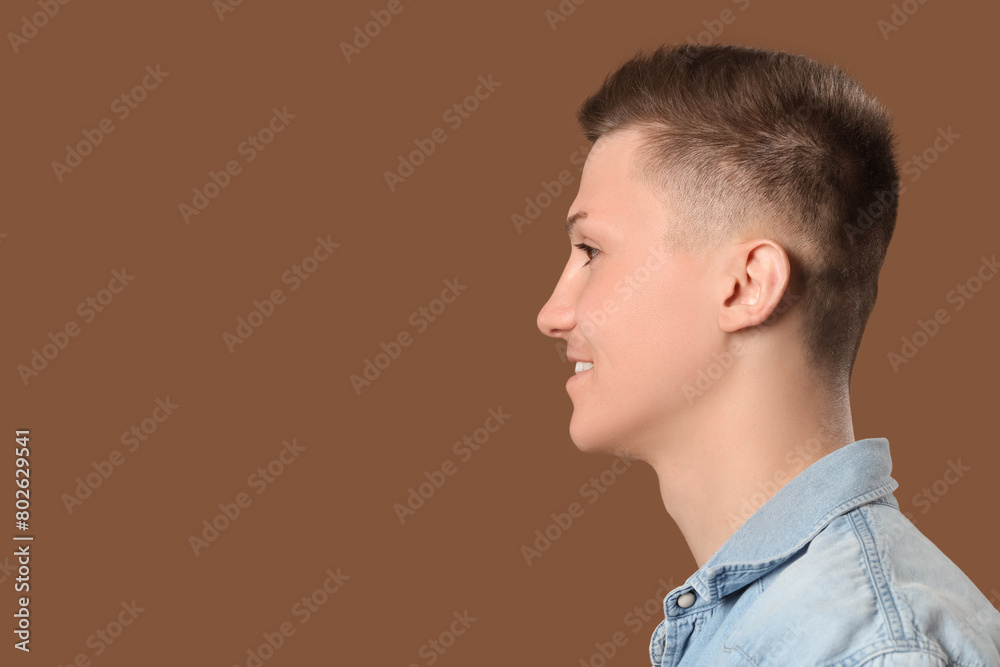 Fototapeta premium Young man with stylish haircut on brown background, closeup