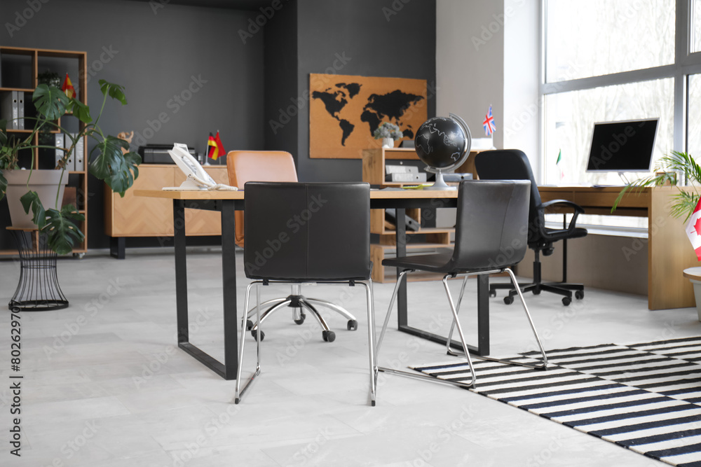 Fototapeta premium Interior of travel agency with tables and flags