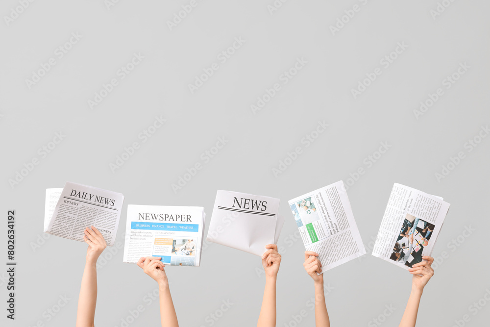 © Pixel-Shot - Female hands with newspapers on grey background © Pixel-Shot - Female hands with newspapers on grey background