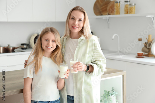 Mother and daughter holding glasses of milk in a modern kitchen, healthy life...