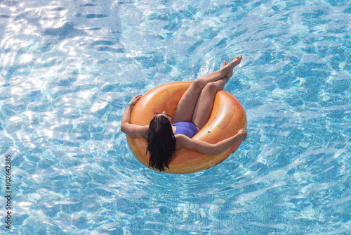 A woman in a swimming pool relaxing on an inflatable ring