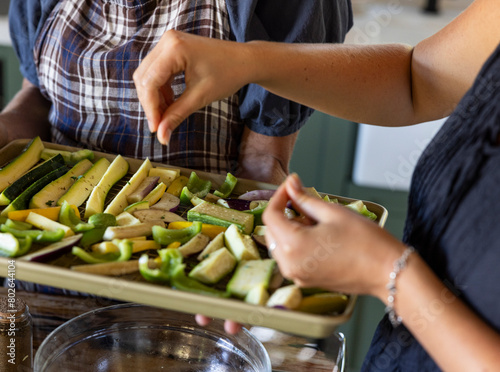 Detail of hand seasoning a tray of roasted vegetables