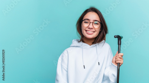 young woman disability advocate holding walking stick, isolated on plain blue color studio background with copy space	
 photo