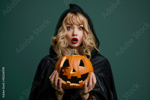 Woman with white makeup and red face paint holding a carved pumpkin, styled for Halloween makeup fashion and beauty modeling
