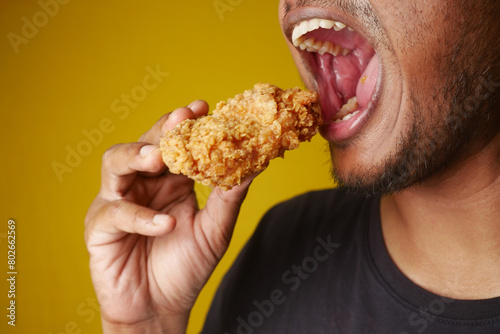 Man enjoying fried chicken, mouth open, savoring every bite with a big smile © Towfiqu Barbhuiya 