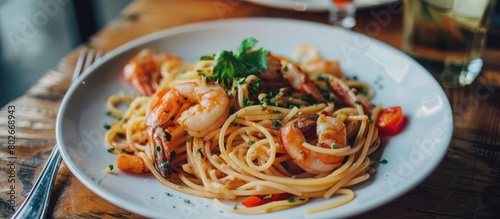 Spicy seafood spaghetti stir-fried and served on a round white plate on a wooden table, with a vintage tone style.