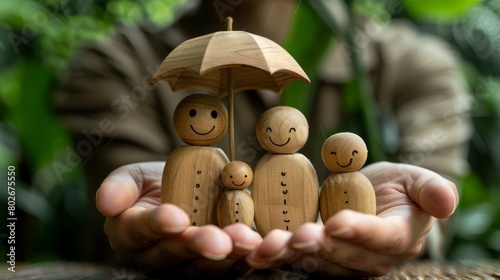 A charming conceptual photo showing wooden family figures protected under a small umbrella, symbolizing insurance or security.