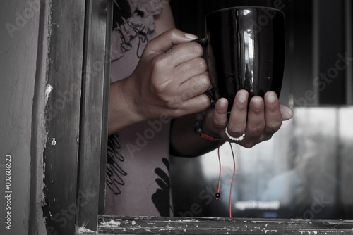 Hand holding a mug in the window frame welcoming the morning