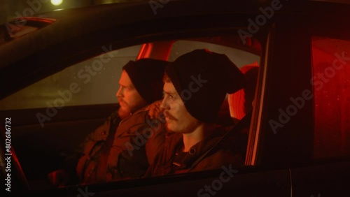 Two men in a car lowering ski masks over their faces