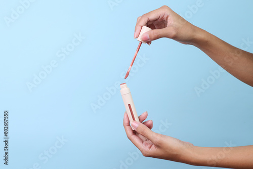 Woman hands hold lipstick for make up isolated on blue background