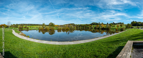 Reservoir lake with green meadow and blue sky in fall