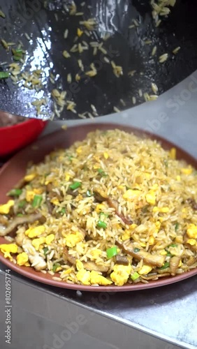 Serving rice dish from wok pan onto plate chifa peruvian chinese dish close-up vertical photo
