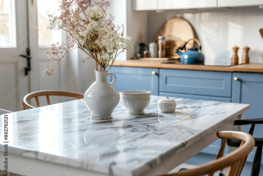 Empty and clean marble dining table in scandinavian kitchen. Modern monochrome interior with blue drawers on wooden furniture. Tablewear and vases with flowers - generative ai Empty and clean marble dining table in scandinavian kitchen. Modern monochrome interior with blue drawers on wooden furniture. Tablewear and vases with flowers - generative ai