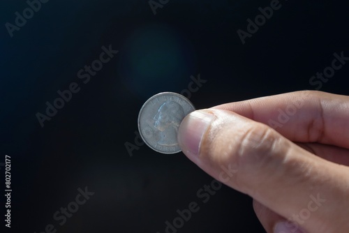 Hand holding an old American quarter dollar coin Liberty 1989 on dark background photo