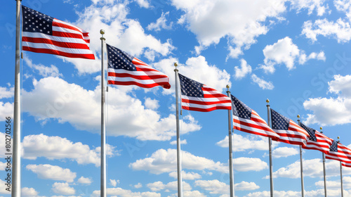 American flags in a row waving against blue sky with clouds