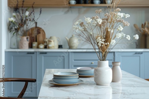 Empty and clean marble dining table in scandinavian kitchen. Modern monochrome interior with blue drawers on wooden furniture. Tablewear and vases with flowers - generative ai