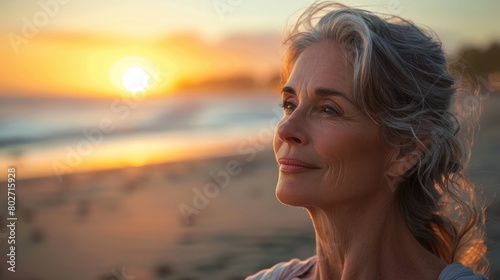 Serene sunset moment with a mature woman enjoying a tranquil beach scene © Fat Bee