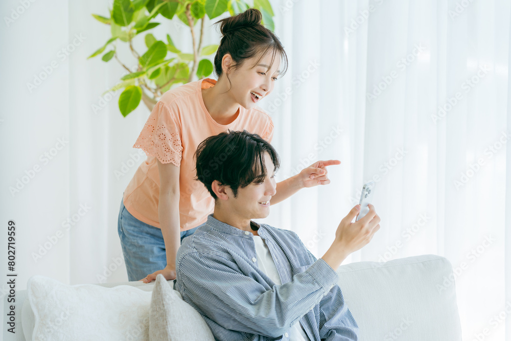 リビングでくつろぎながらスマホを見る若いカップル	