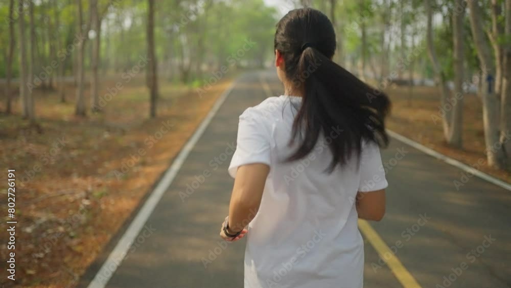 Happy young Asian woman running alone at a local running park in the morning Happy young Asian woman running alone at a local running park in the morning