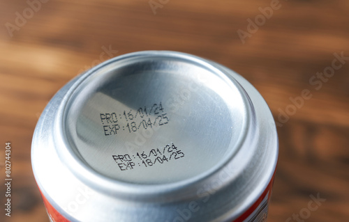 An aluminum beer can on a wooden background, close-up. Expiration date on a beer can.