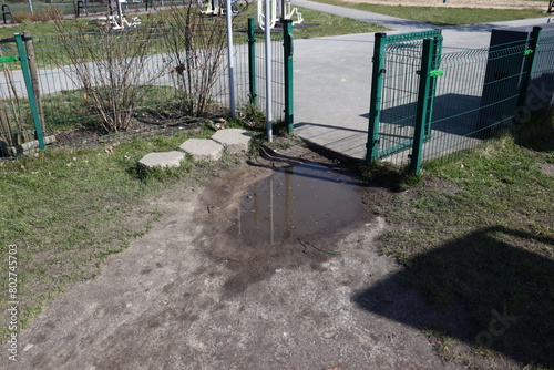 A puddle at the gate. A puddle makes it difficult to get to the playground