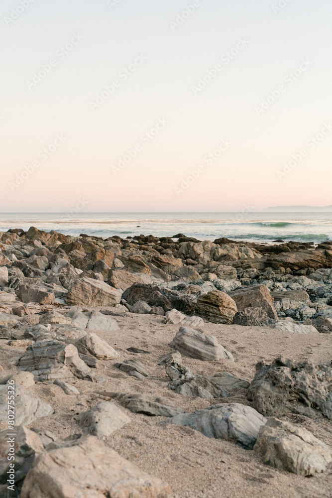 Pastel dusk settles over a serene, rocky shoreline Pastel dusk settles over a serene, rocky shoreline