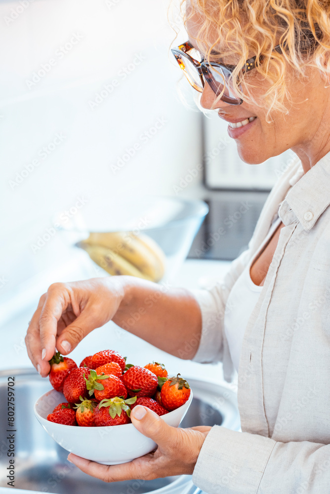 One midage woman at home with fresh bowl of red strawberries seasonal fruit. Concept of weight loss and calorie deficit count. Eating natural dieting healthy people female lifestyle. Strawberry fruits One midage woman at home with fresh bowl of red strawberries seasonal fruit. Concept of weight loss and calorie deficit count. Eating natural dieting healthy people female lifestyle. Strawberry fruits