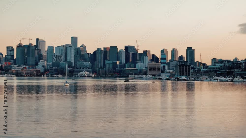 A single sailboat rests on the reflective water in Lake Union at dusk in front of the Seattle skyline and Space Needle A single sailboat rests on the reflective water in Lake Union at dusk in front of the Seattle skyline and Space Needle