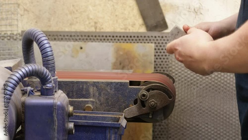 Worker Sanding Metal Block On A Belt Sander, Closeup Shot photo