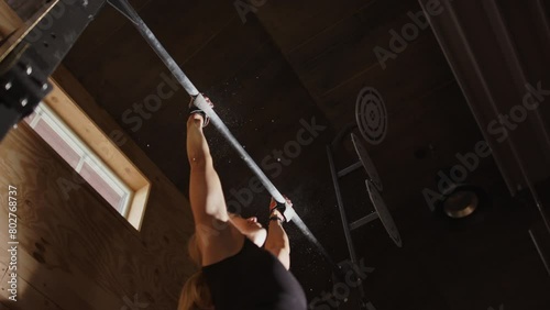 Woman use momentum to do CrossFit kipping pull ups. Tight upwards slomo view photo