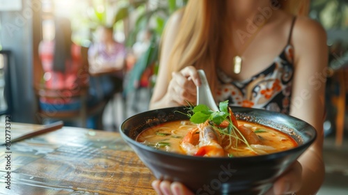 A food blogger capturing the beauty of a bowl of Tom Yum Goong soup in a stylish cafe setting, highlighting its appeal as a trendy and delicious dish. photo