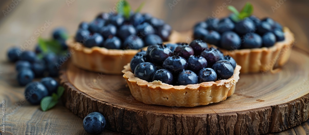 Healthy dessert tart snack of blueberry tarts displayed on a wooden platter.